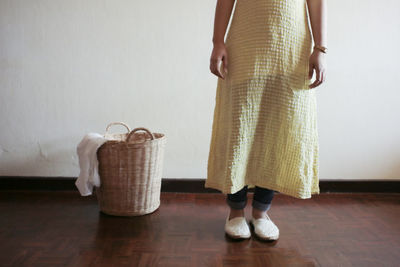 Low section of woman standing on floor against wall