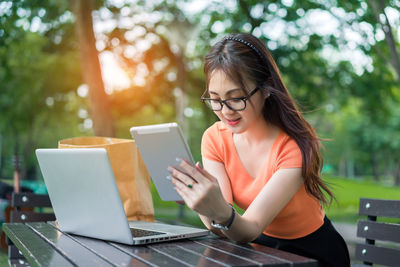 Young woman using mobile phone while sitting on table