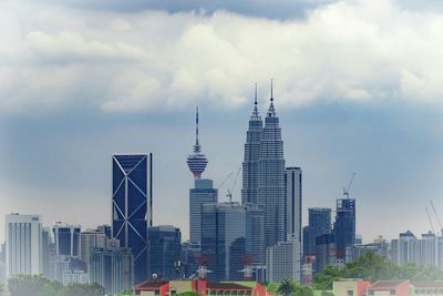 Skyscrapers in city against cloudy sky