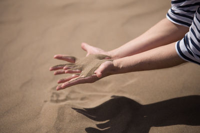 High angle view of hands on sand