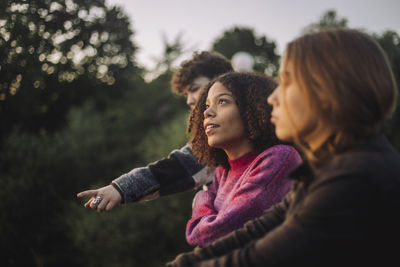 Thoughtful girl day dreaming with friends at sunset