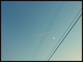 Low angle view of power lines against clear blue sky