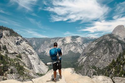 Rear view of man looking at mountains against sky