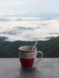 Coffee cup on table against sky
