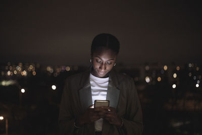 Businesswoman text messaging on smart phone at night