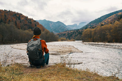 Rear view of man looking at mountains against sky