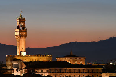 Illuminated buildings in city against sky at night