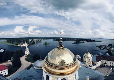 High angle view of buildings and sea against cloudy sky