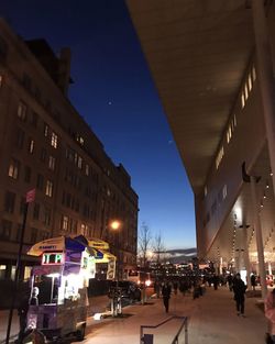 People on illuminated street amidst buildings at night