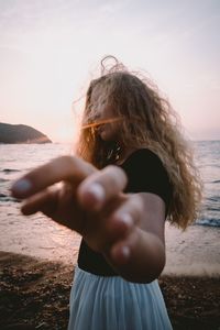 Midsection of woman standing at beach against sky