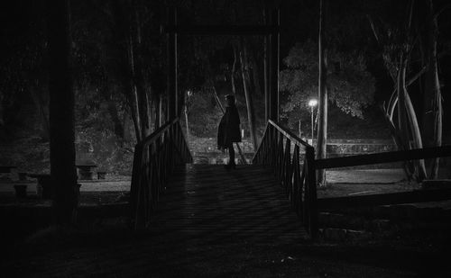 Rear view of woman walking on walkway at night