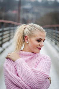 Smiling young woman standing on footbridge in city