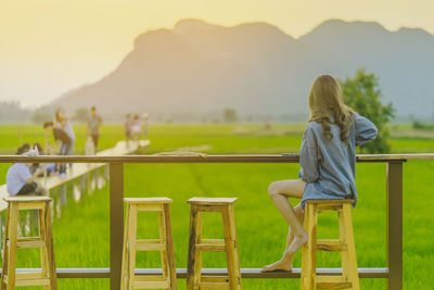 Rear view of woman sitting on chair in field