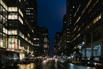 Illuminated city street against clear sky at night