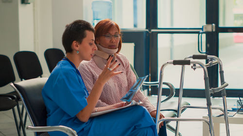 Young woman using mobile phone while sitting on chair