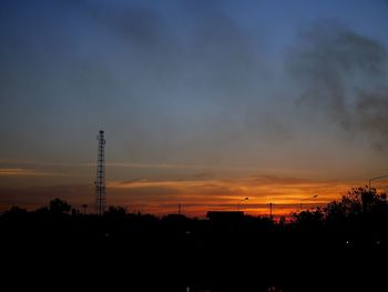 Silhouette of electricity pylon against dramatic sky