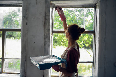 Rear view of woman standing by window