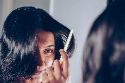 Reflection of woman combing hair on mirror