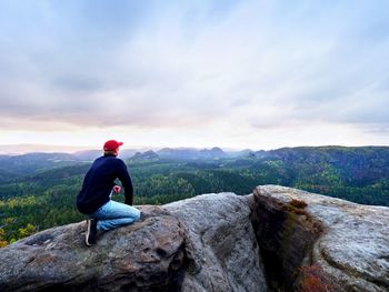 Rear view of man sitting on rock