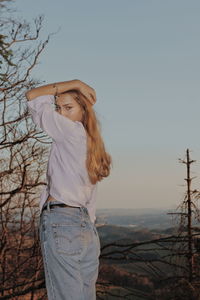 Young woman standing against sky