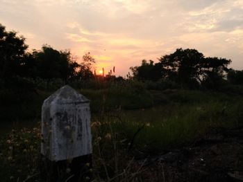 Cemetery on field against sky at sunset