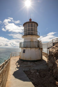 Lighthouse by sea against sky