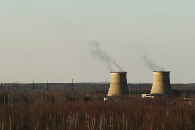 Smoke emitting from factory against clear sky