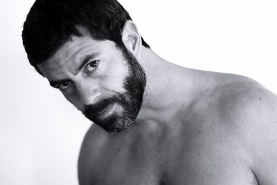 Close-up portrait of shirtless man against white background