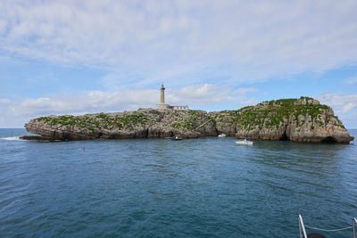 Lighthouse by sea against sky