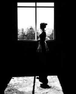 Side view of woman standing by window