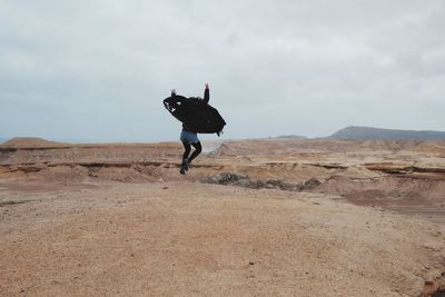 Rear view of woman jumping on sand at desert