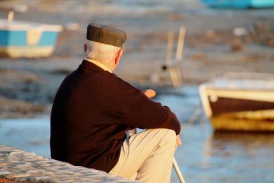 Rear view of man sitting on coastline