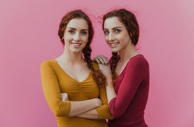 Portrait of smiling siblings against pink background