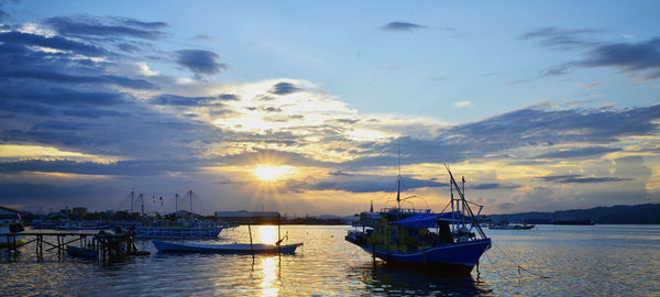 Boats in sea at sunset