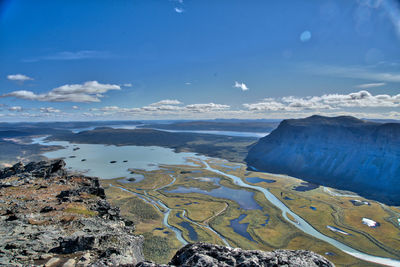 Aerial view of river by mountains against cloudy sky