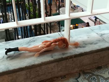 High angle view of woman lying down on railing at home