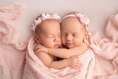 High angle view of twins lying on bed
