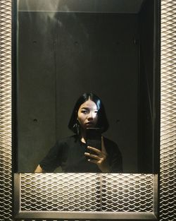 Reflection of woman taking selfie from mobile phone on mirror