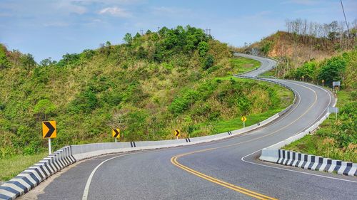 Scenic view of road amidst trees against sky