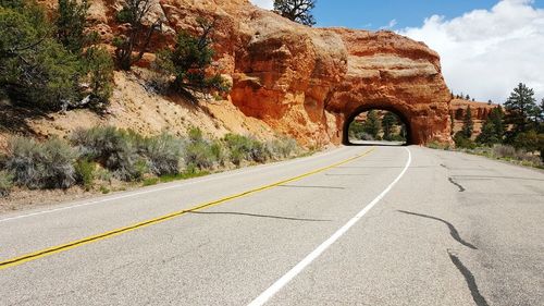 Empty road by tunnel against sky