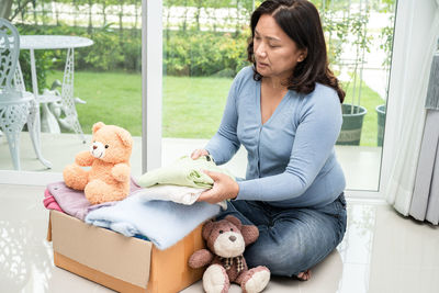 Young woman with teddy bear on sofa at home