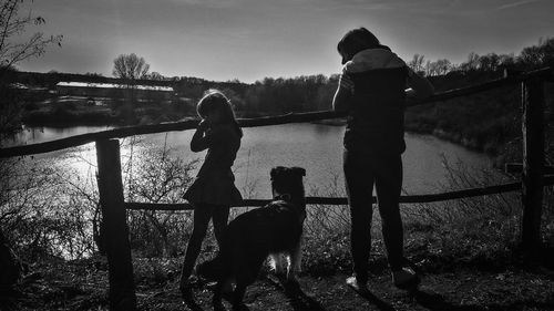 Rear view of woman with dog standing against sky