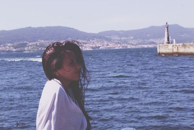 Woman standing by sea against sky