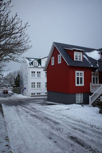 Snow covered road amidst buildings against sky