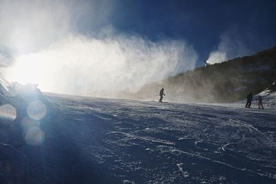 Snowmaking on slope. skier near a snow cannon making fresch powder snow. ski resort and winter