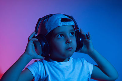 Cyberpunk boy child in a white t shirt and large headphones listening to music on the background 