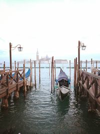 Wooden posts in sea against clear sky