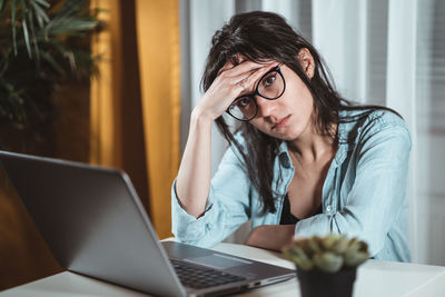 Frustrated young woman by laptop in office