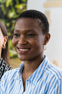 Smiling african american female with short hair and charming smile looking away on blurred background