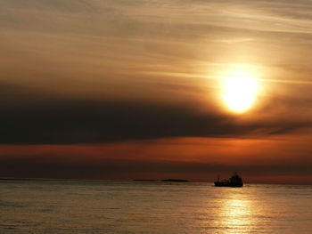 Silhouette boat sailing on sea against sky during sunset